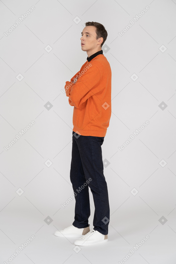 A man in an orange sweater stands with his arms crossed