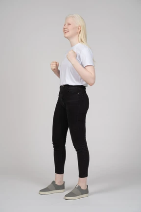 Three-quarter view of a young woman smiling with her fists up