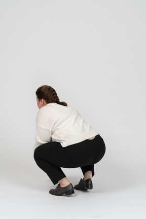 Rear view of a plump woman in casual clothes squatting