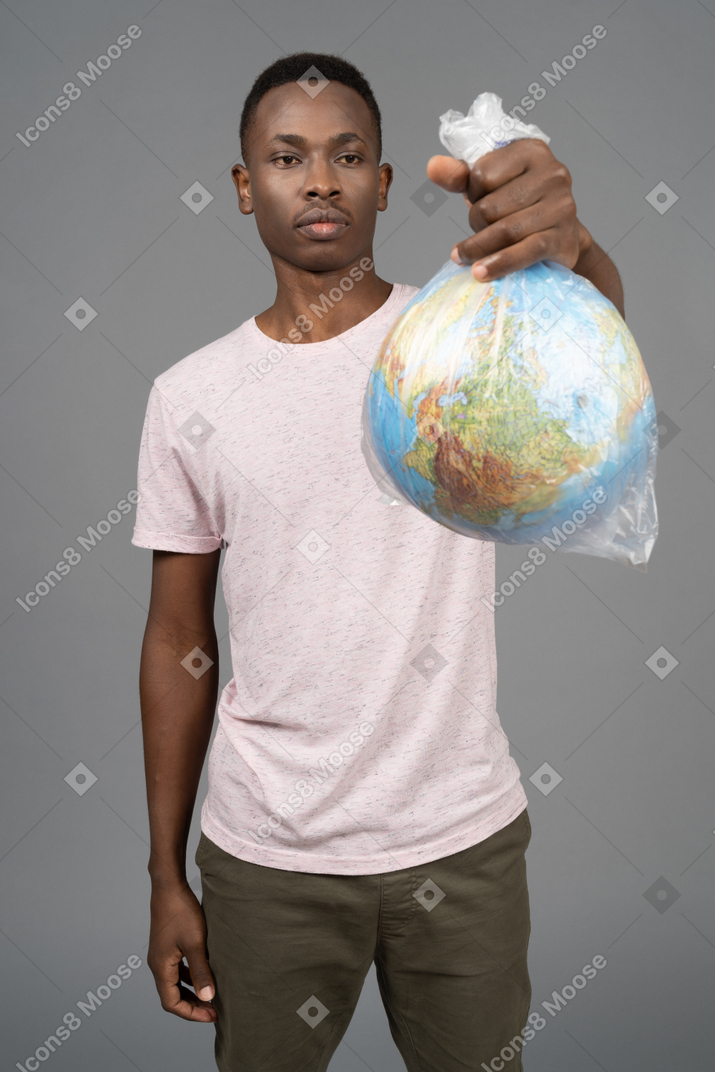 一个小伙子手持与地球地球仪的白色塑料