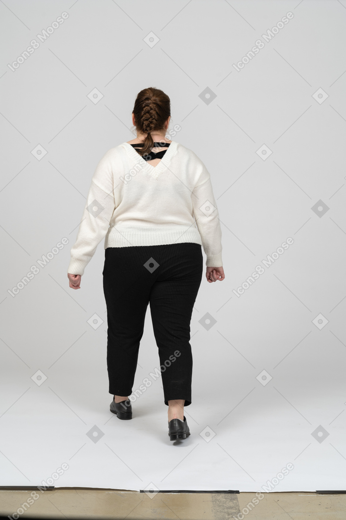 Retrovisor de uma mulher gorducha com roupas casuais caminhando