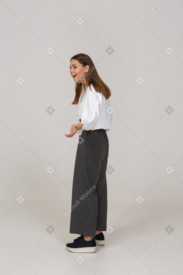 Vista lateral de uma jovem maravilhada com roupas de escritório estendendo as mãos