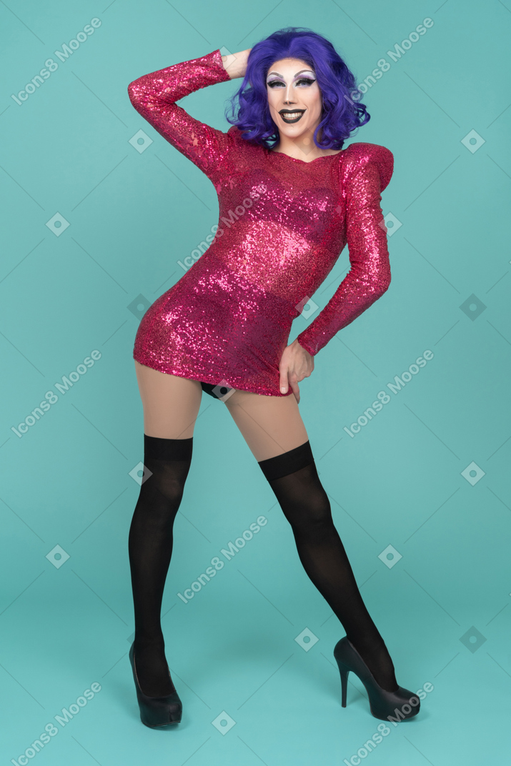 Ritratto di una drag queen in abito rosa sorridente mentre assume una posa sicura