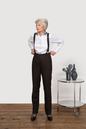 Front view of an old lady in office clothing adjusting her trousers