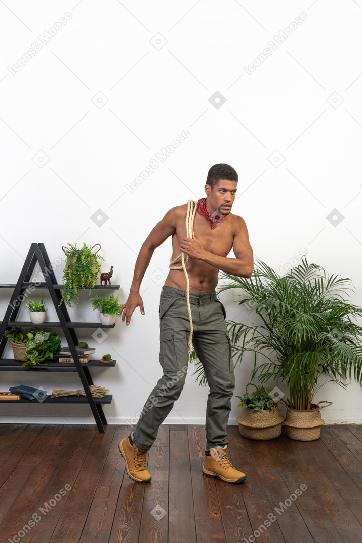 Strong young man running with a coil of rope on his shoulder