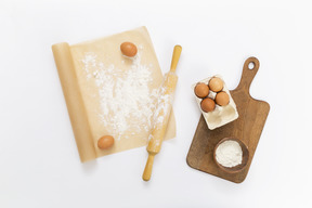 Baking paper, rolling pin, eggs and cutting board