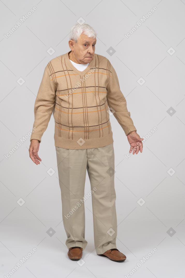 腕を伸ばして立っているカジュアルな服装で混乱した老人の正面図