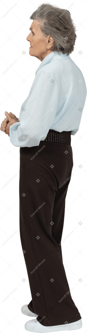 Vue latérale d'une vieille femme sérieuse vêtue d'un chemisier et d'un pantalon se tenant la main ensemble