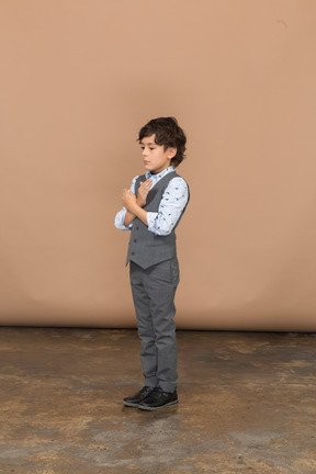 Vista lateral de um menino de terno cinza mostrando o gesto de parada