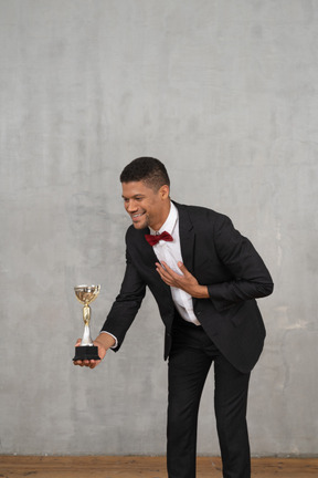 Man in suit presenting an award to someone small