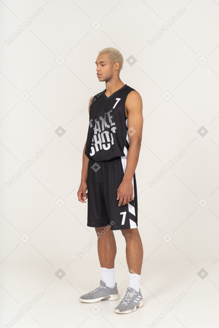 目を閉じて立っている若い男性のバスケットボール選手の4分の3のビュー