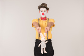 Male clown holding toy rabbit