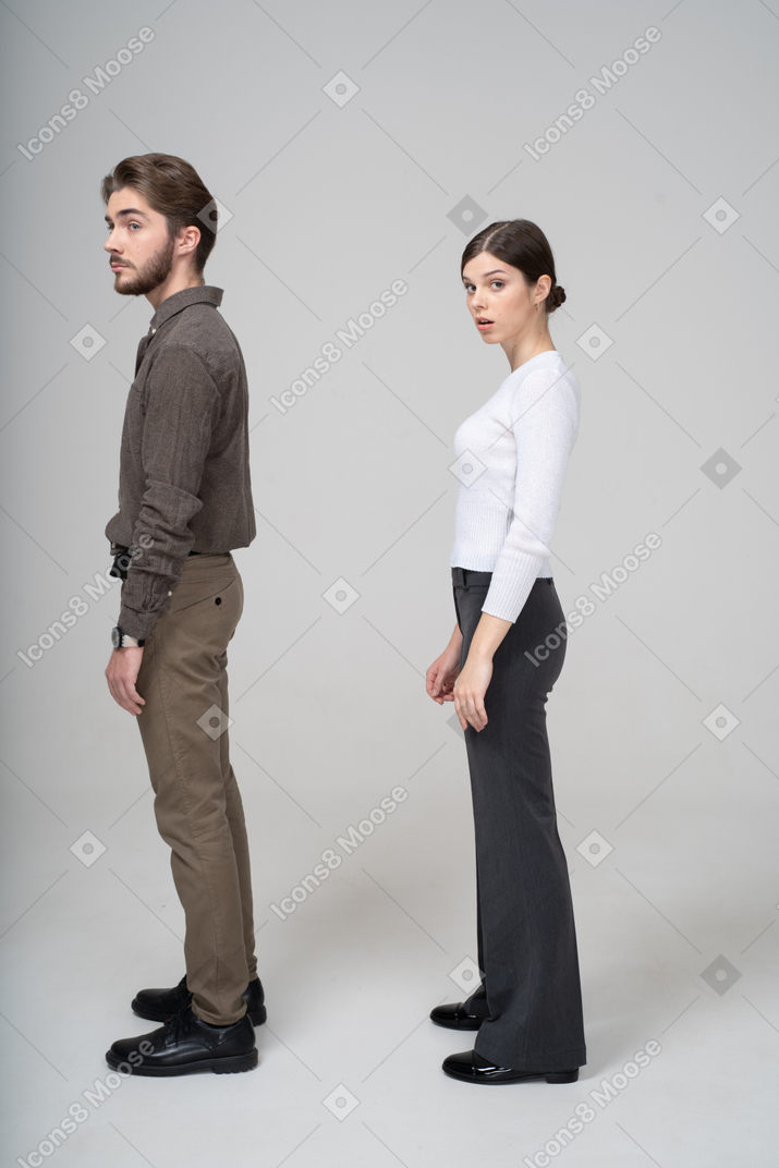 Vista lateral de um jovem casal surpreso com roupas de escritório