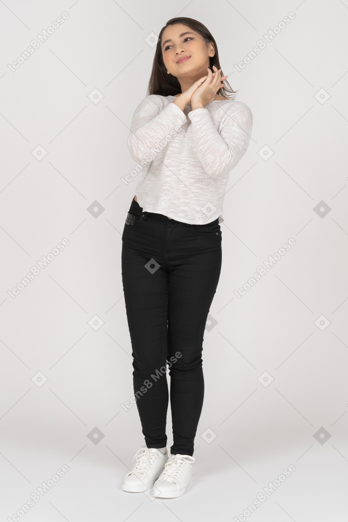 Delighted young woman keeping hands together next to her face