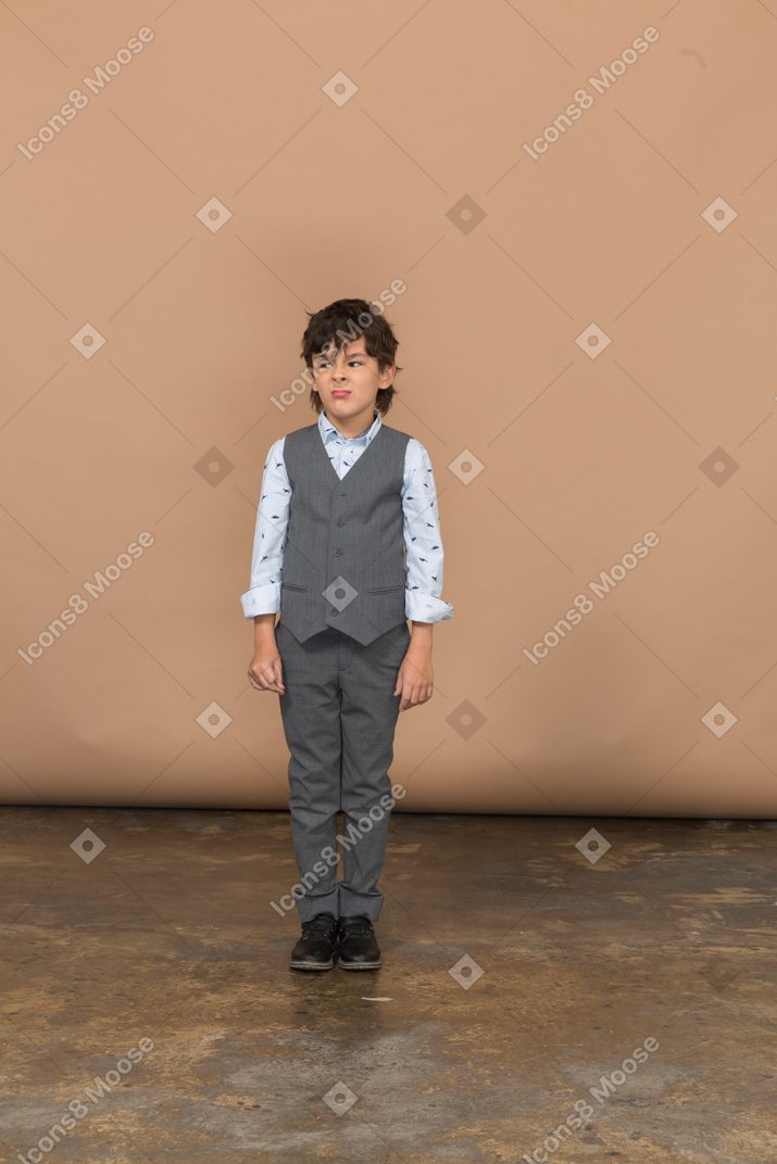 Front view of a cute boy in grey suit standing still