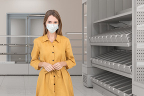 A woman wearing a face mask standing in front of shelves