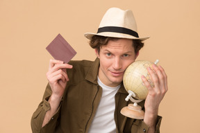Gut aussehender junger mann mit einem globus und reisepass