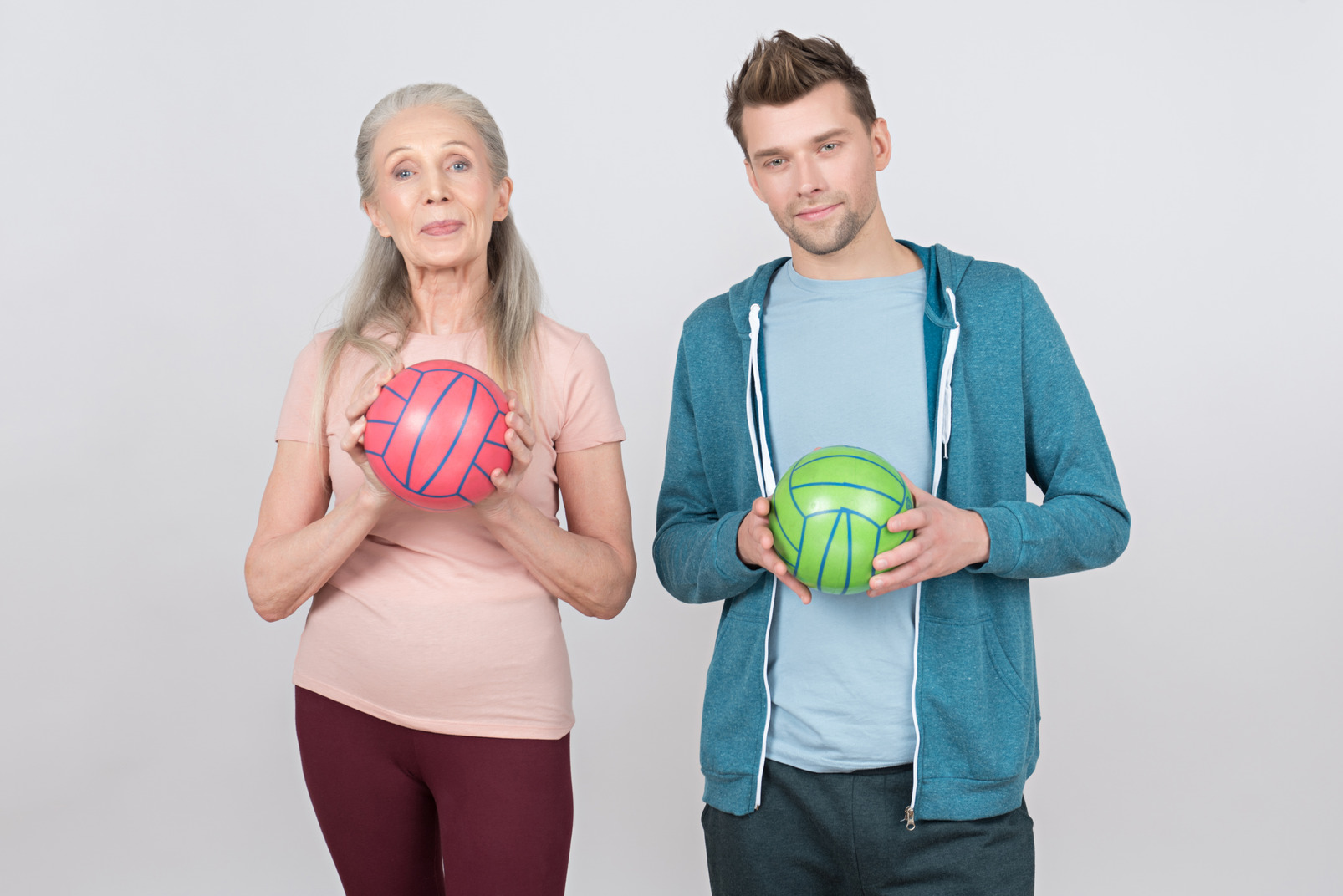 Old woman and young guy in sports wear holding balls