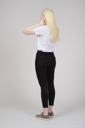 Back view of blonde woman covering her ears