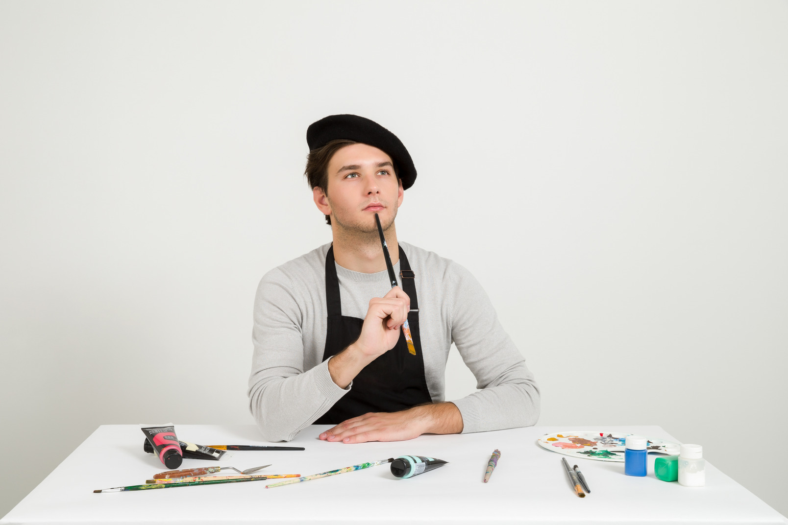 Pensive handsome male artist holding brush