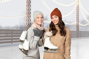 Two women standing next to each other holding skates