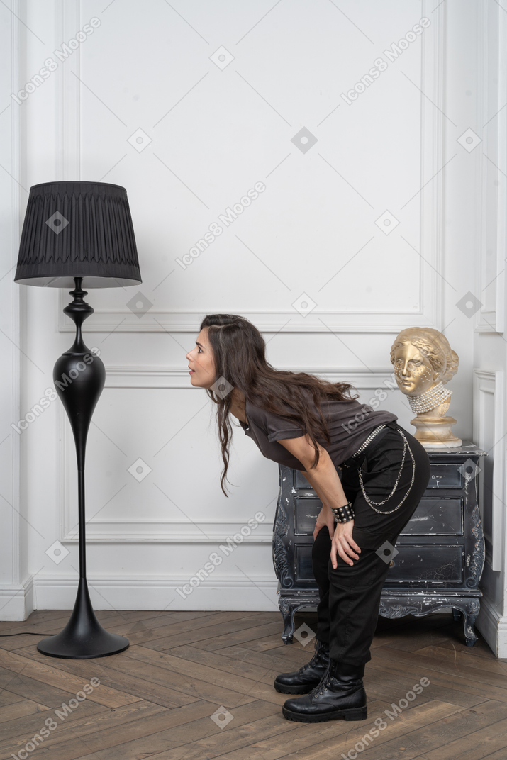 Vista lateral de una mujer rockero cuestionando inclinándose hacia adelante en un pasillo