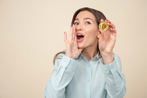 Chica joven atractiva sosteniendo bitcoin y gritando algo