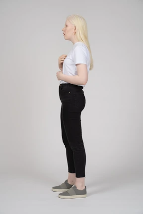 Profile view of a young woman in casual clothes pointing at herself