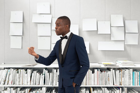 A man in a tuxedo standing in front of a bookshelf