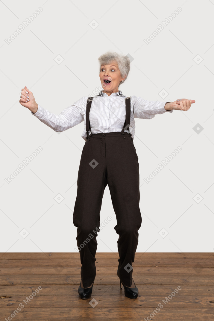 Вид спереди счастливой старушки в офисной одежде, поднимающей руки во время крика