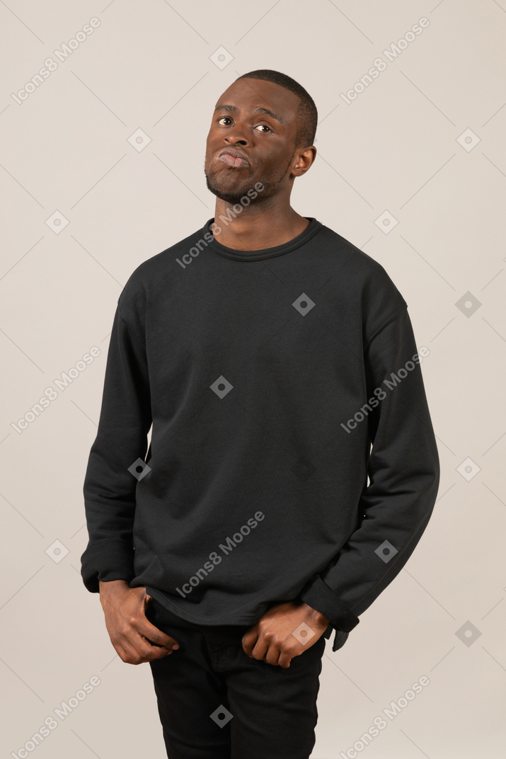 Black man with hands in pockets thinking