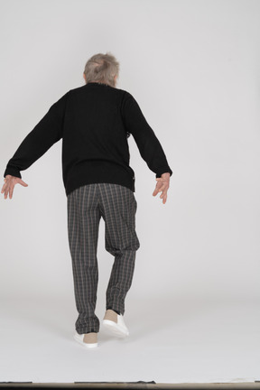 Elderly man walking away with arms extended backwards