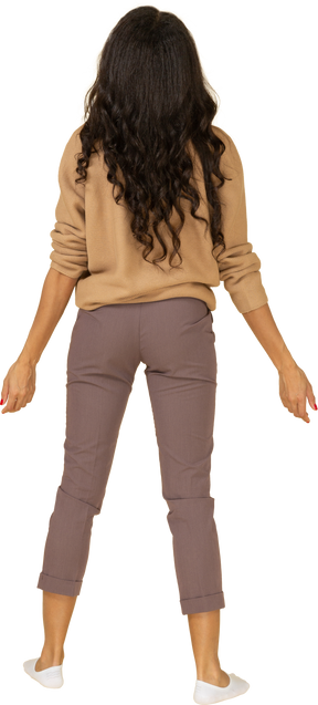 Vista posteriore di una giovane donna dalla pelle scura in piedi con le braccia larghe