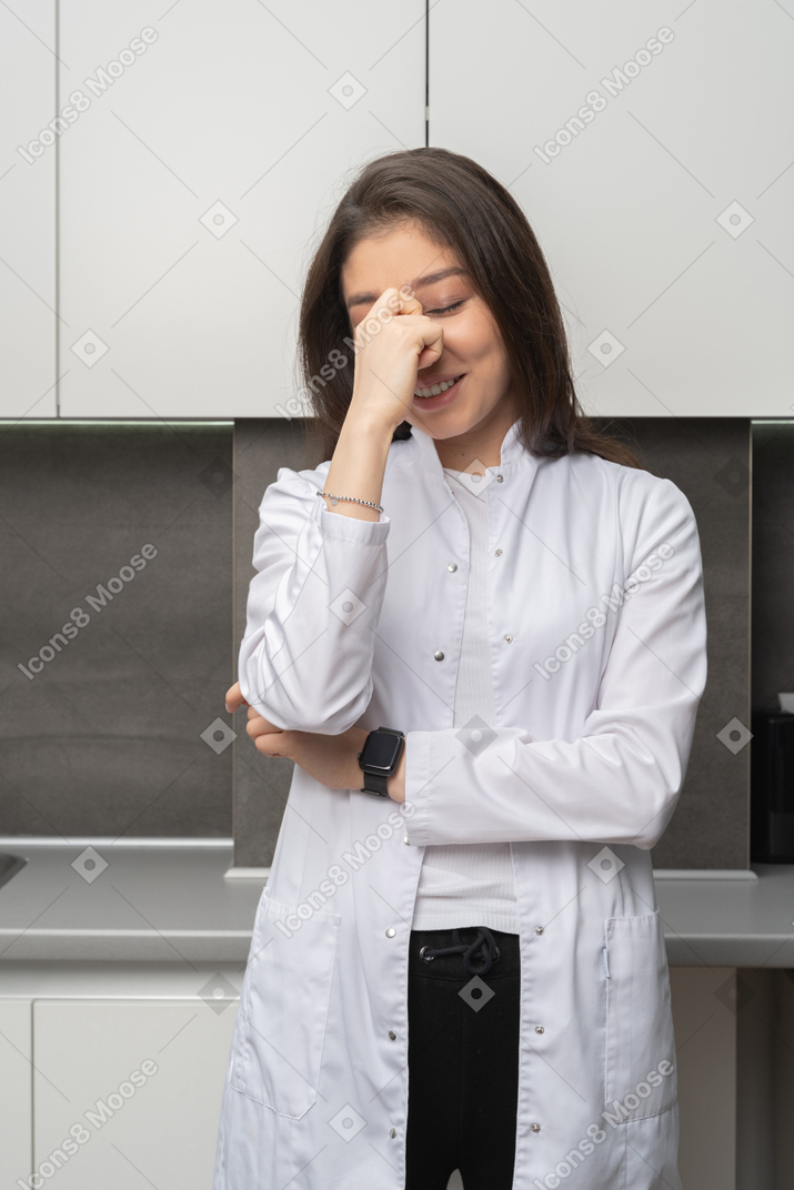 Front view of a shy female smiling doctor hiding face