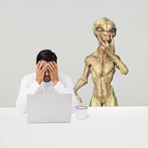 Tired man in an office with an alien standing near him