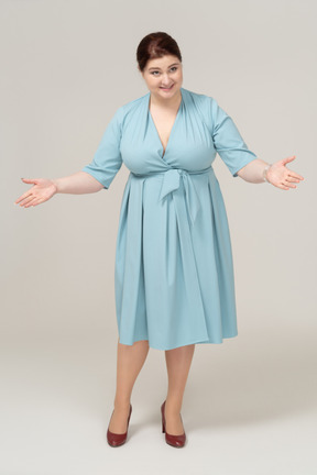Vista frontal de uma mulher de vestido azul cumprimentando alguém