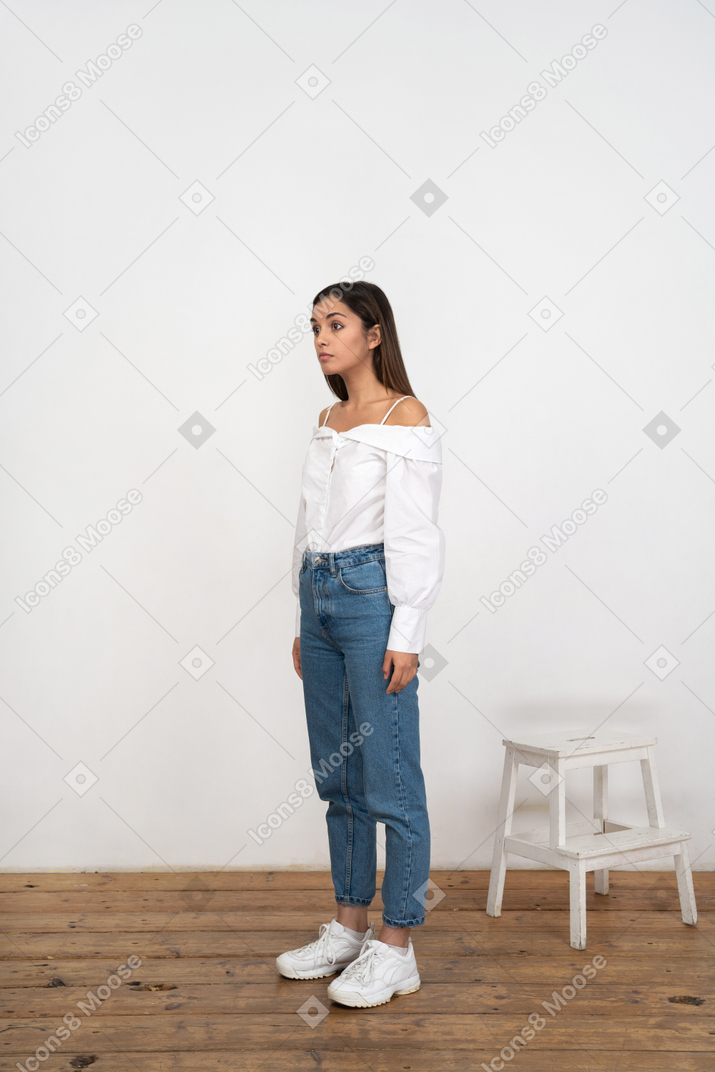 Woman standing on wooden floor in white shirt and jeans