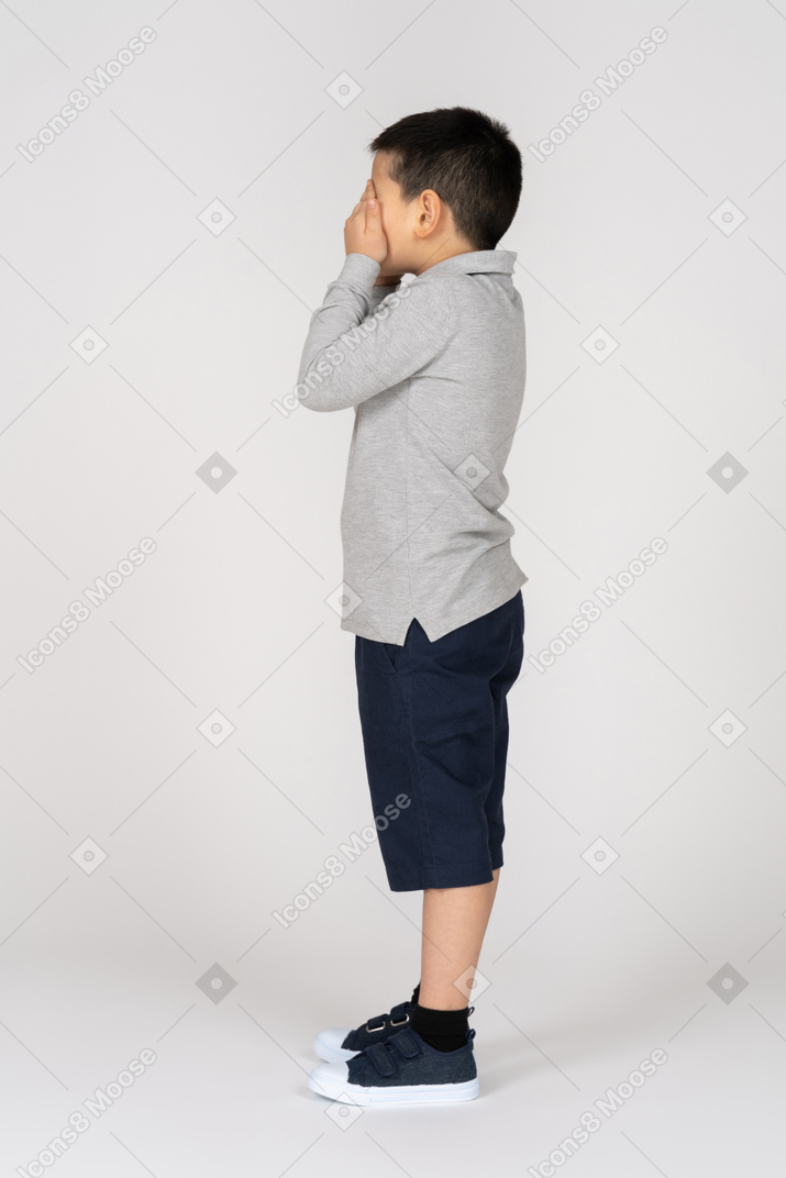 Boy covering his eyes in profile