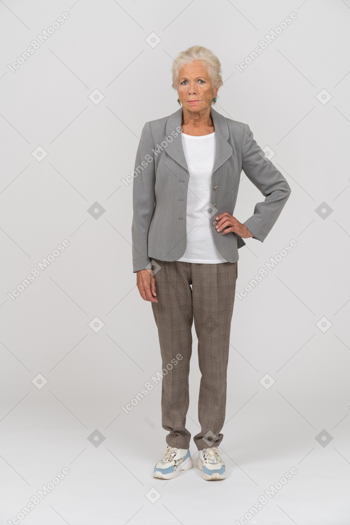 Vista frontale di una vecchia signora in abito in posa con la mano sull'anca