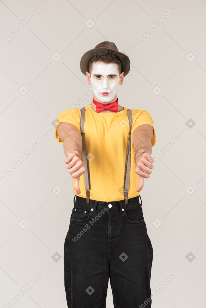 Sad looking male clown showing thumbs down with both hands