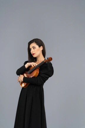 Vista de tres cuartos de una joven vestida de negro sosteniendo el violín