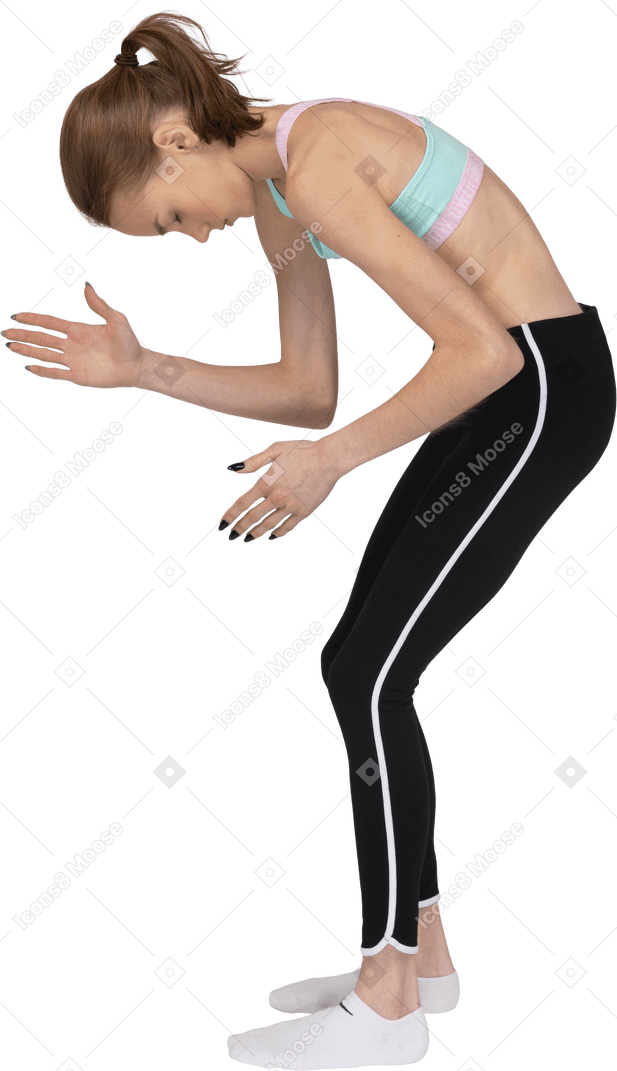 Vista lateral de una jovencita en ropa deportiva agacharse y levantar las manos