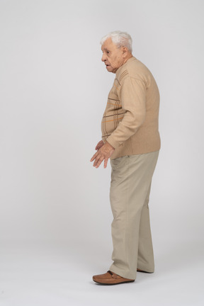 Вид сбоку на старика в повседневной одежде, идущего
