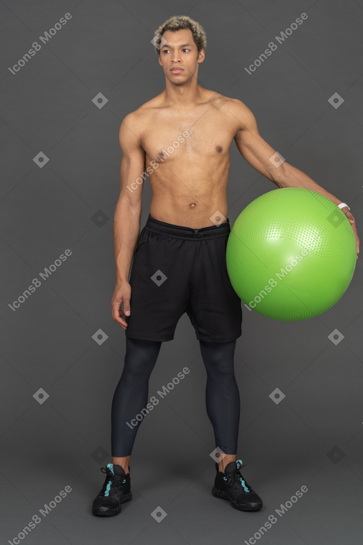 Athletischer mann, der einen fitnessball hält
