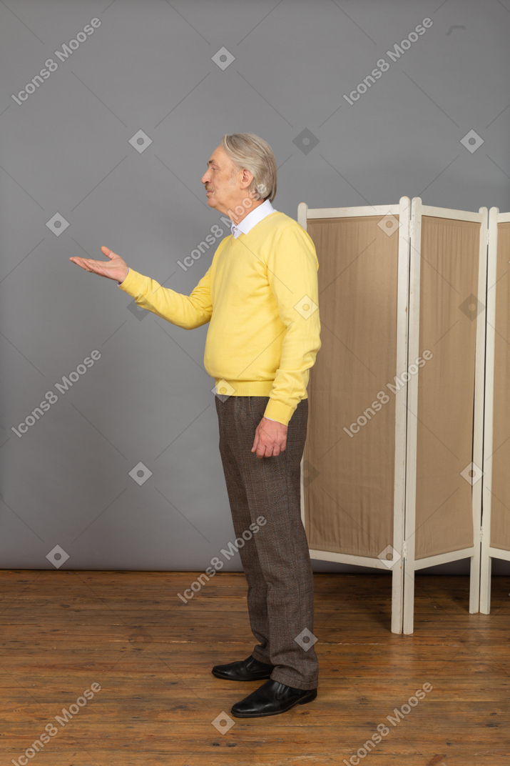 Side view of a questioning old man raising his hand