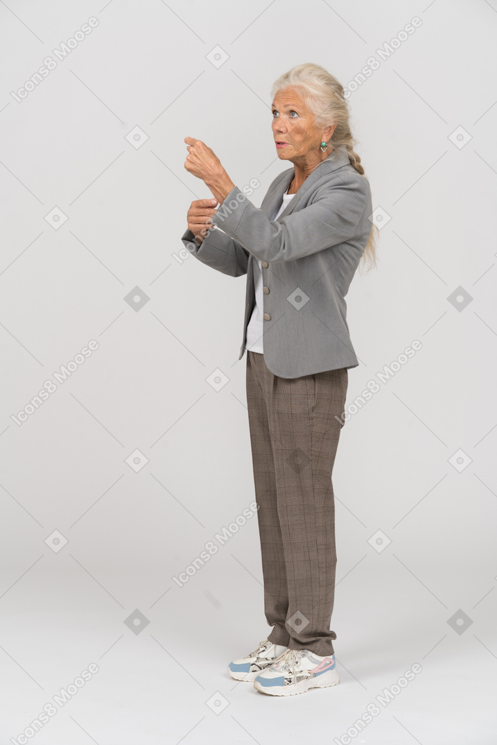 Вид сбоку пожилой дамы в куртке, указывающей пальцем