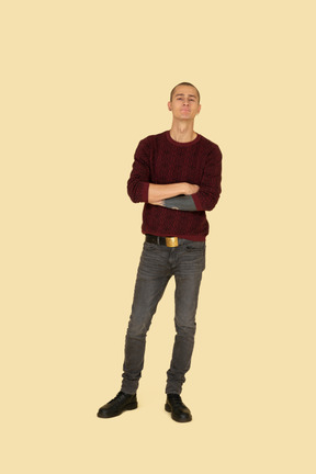 Front view of an offended young man dressed in casual clothes crossing his hands