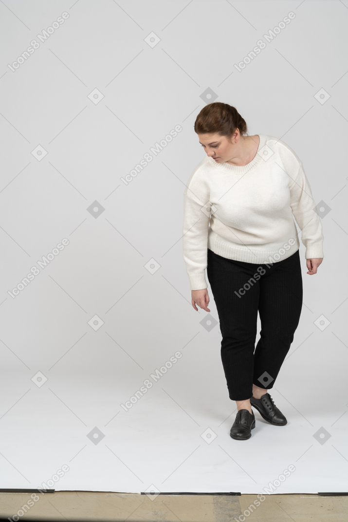 Vista frontal de una mujer regordeta en ropa casual mirando hacia abajo