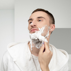A man shaving his face in a bathroom