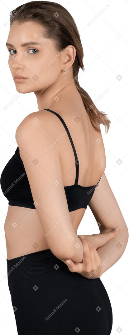 Vista posteriore di tre quarti di una giovane donna con la pelle chiara che si tiene per mano dietro